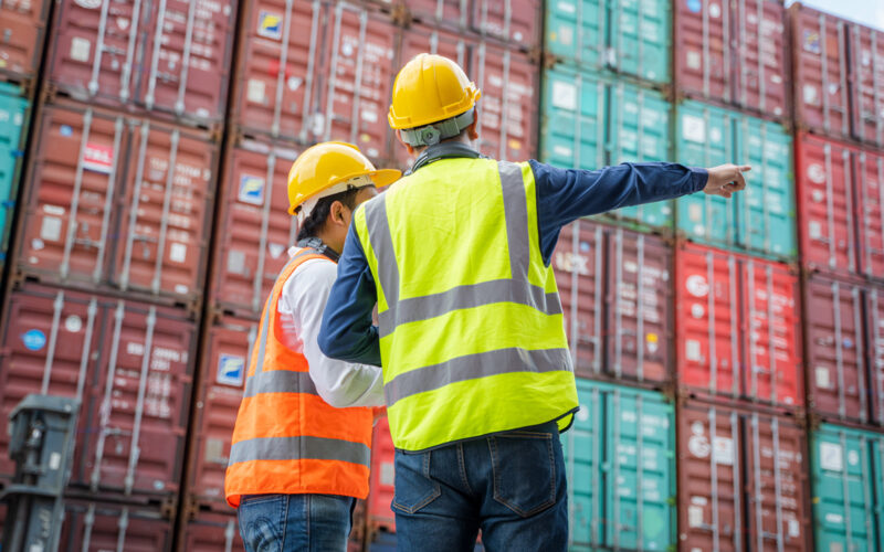 To medarbejdere laver kvalitetskontrol af ​​containere fra fragtskib til eksport og import